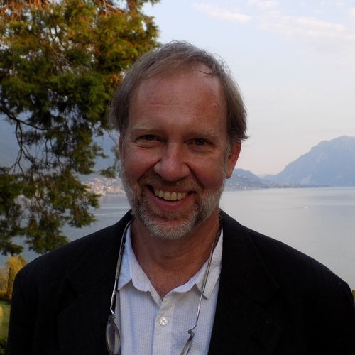 Headshot of author Carl Elliott in front of a lake with mountains in the distance